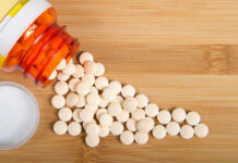 The Shocking Side of Heartburn Pills Spilled white pills from a prescription bottle on a wooden surface