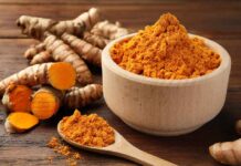Turmeric Breakthrough: PMS Relief That’s Real? Turmeric powder in a wooden bowl with fresh turmeric roots