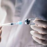 A healthcare professional preparing a syringe from a vial