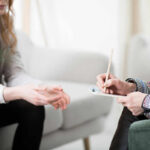 AI Therapy Scandal: 15 Ethical Risks Unveiled Two individuals engaged in a counseling session, one taking notes