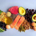 Grandma Remedy Beats Fiber Supplements in Gut Health Showdown An assortment of healthy foods including fish, nuts, fruits, and vegetables arranged on a light background