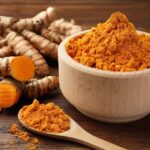 Ancient Spice vs. Modern Medicine: The Gut Showdown Turmeric powder in a wooden bowl with fresh turmeric roots