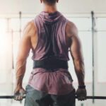 Deadlift Mistakes That Destroy Your Back A muscular person preparing to lift a barbell in a gym setting