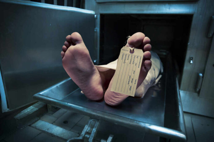 Feet of a deceased person on a metal table with an identification tag
