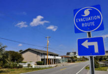 Evacuation route sign with a left turn arrow near residential buildings