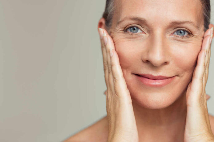Close-up portrait of a smiling woman gently holding her face