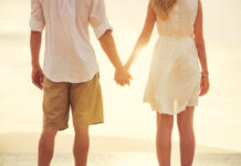 Couple holding hands at the beach during sunset