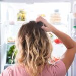 Foods That Lead To The Sharpest Cognitive Decline Person looking into an open refrigerator