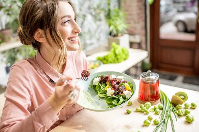 Woman eating a fresh salad at a bright cafe