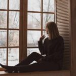 Person sitting on a windowsill looking outside