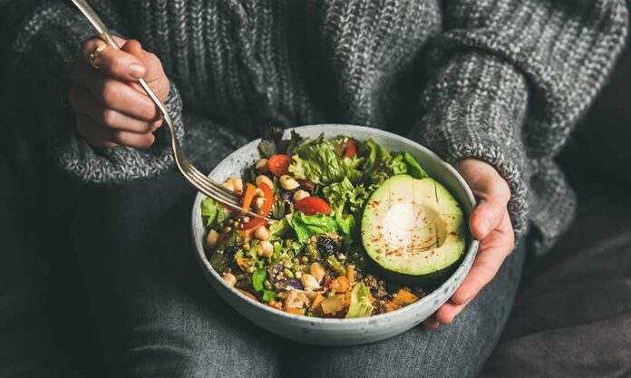 shutterstock_1317602774-1 person holding a bowl of salad with avocado