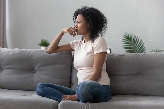 Woman sitting on a gray sofa looking thoughtful