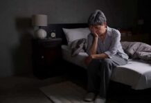 Midnight Pee Trips Aren’t Random — Here’s Why Older adult sitting on bed with head in hand