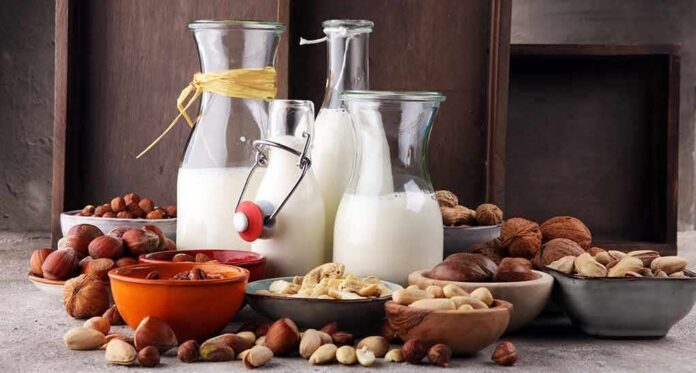 shutterstock_1029826861 Glass bottles of milk surrounded by assorted nuts in bowls