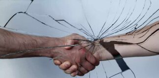 Handshake seen through cracked glass