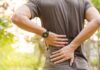 person holding lower back outdoors