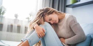 Woman holding her stomach in pain on a sofa