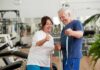 Older couple in gym smiling and holding a measuring tape