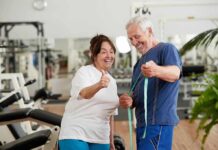 Lift Heavy, Age Backward? Older couple in gym smiling and holding a measuring tape