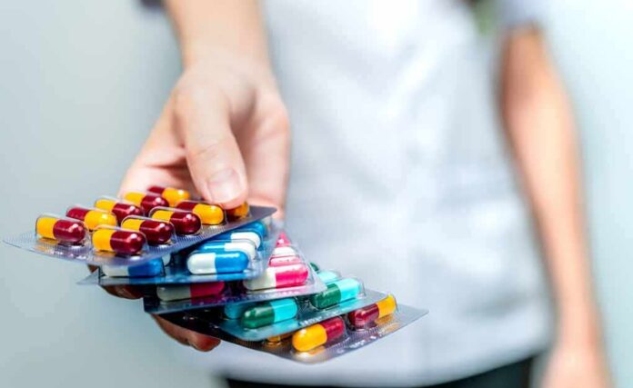 shutterstock_1444962308 Hand holding blister packs of assorted capsules