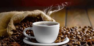 steaming cup of coffee among roasted beans