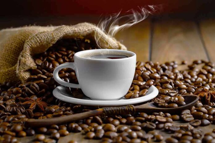 steaming cup of coffee among roasted beans