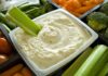 Celery dipped in creamy vegetable dip in a tray of fresh veggies