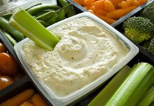 Celery dipped in creamy vegetable dip in a tray of fresh veggies
