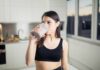 Protein Shake Myth Shattered Woman in sportswear drinking a smoothie in a kitchen