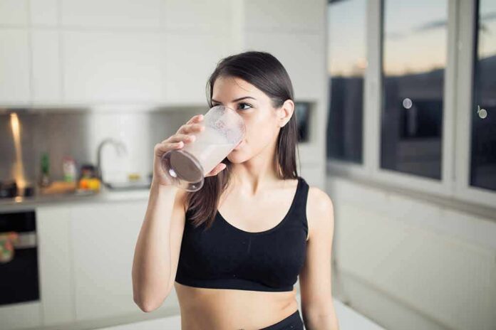 shutterstock_385221889-1 Woman in sportswear drinking a smoothie in a kitchen