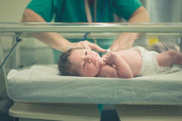 Newborn baby in hospital bassinet being cared for by nurse