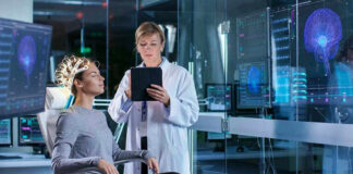 Patient wearing EEG cap sits while clinician reviews data on tablet