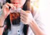 Soda And Booze Spike Gout Risk person sipping iced drink from a glass mug with a straw
