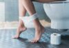 Every Urine Color and What It Means Person sitting on a toilet with underwear at ankles and toilet paper nearby