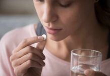 GLP-1 Crash: Why Patients Land in ERs Woman holding a white pill and a glass of water