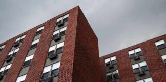 Brick apartment buildings with window air conditioners under cloudy sky