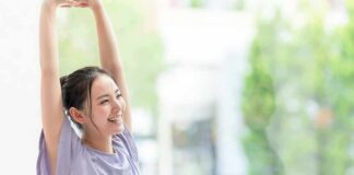 woman stretching with arms raised indoors near window
