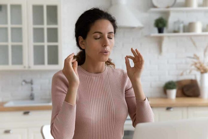 Woman meditating with closed eyes in a kitchen
