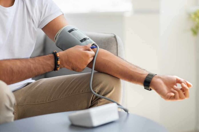 shutterstock_2032749821 Man checking blood pressure at home