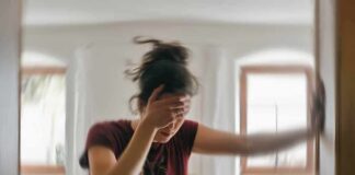 Woman holding her head and steadying herself in a blurred room
