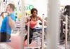How Strength Training Affects Mood & Mental Health Woman lunging on sled in gym next to man using cable machine