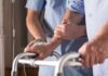 Elderly person using a walker with caregiver support