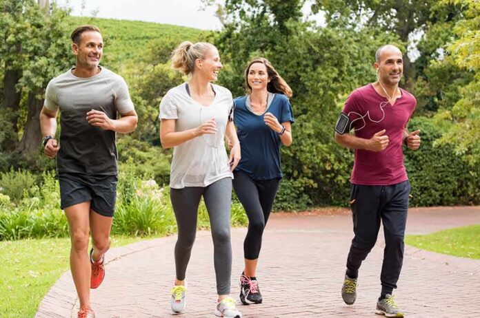 shutterstock_613868252 Group of four adults jogging on a park path