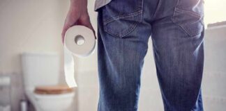 Person holding a toilet paper roll in a bathroom