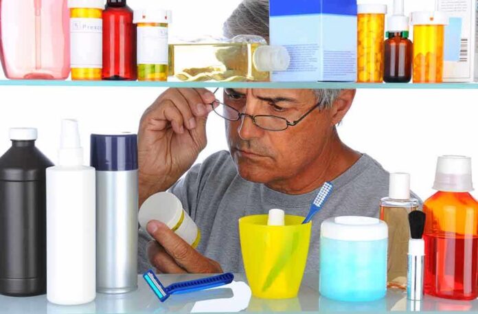 shutterstock_84519838 Man reading a pill bottle in a bathroom cabinet